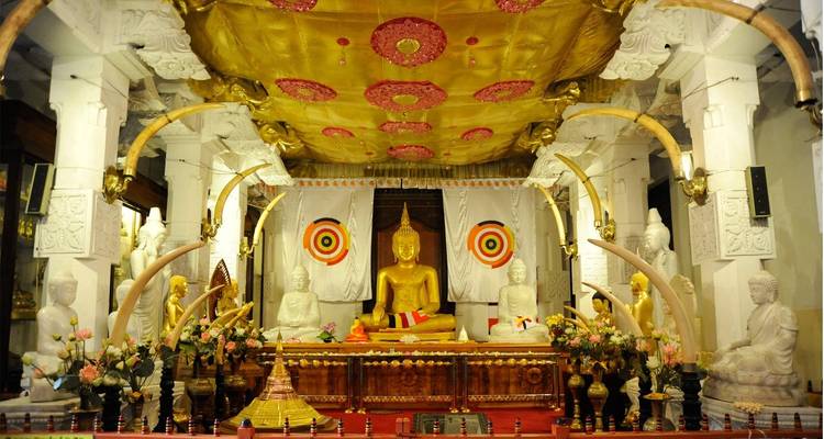 Golden Buddha statue surrounded by ornate decorations inside a temple.