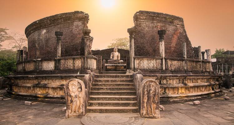 Ruinas antiguas con una estatua de Buda en el cálido resplandor del atardecer.
