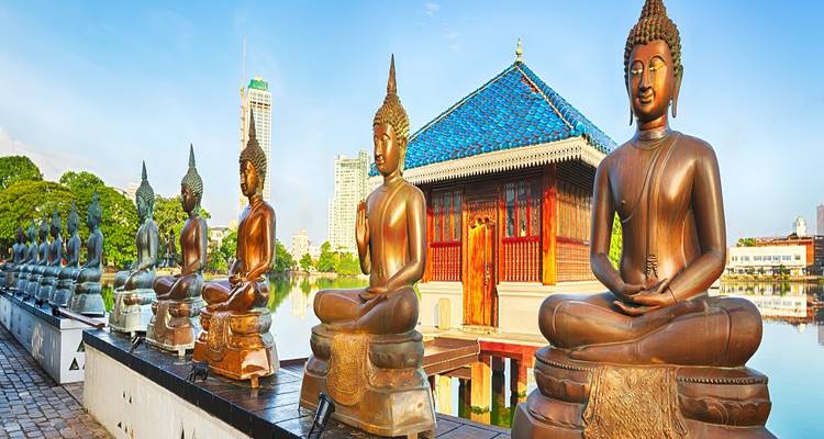 Estatuas de Buda en un templo en Colombo con un telón de fondo del paisaje urbano moderno.