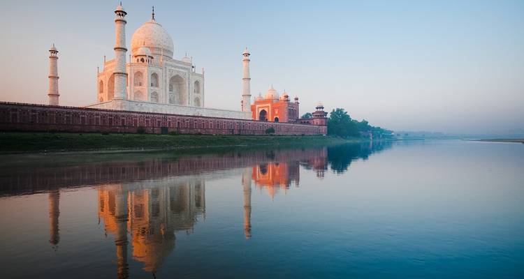 Taj Mahal reflected in a river at sunrise.