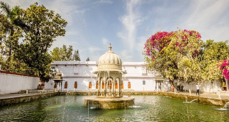 Ornate garden with a fountain and colorful foliage.