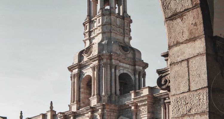 Clocher en pierre de la Cathédrale d'Arequipa encadré par une arche sous un ciel dégagé