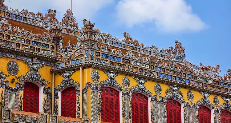 Detalles arquitectónicos ornamentados de un edificio histórico con contraventanas rojas.