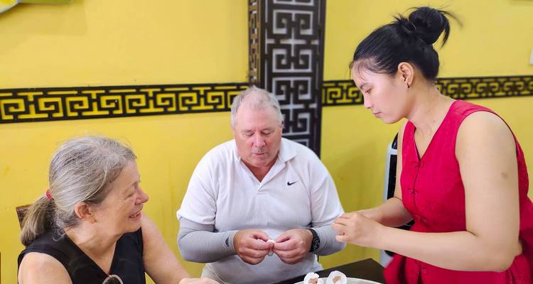 Dos turistas siendo servidos comida por un local en un entorno tradicional.