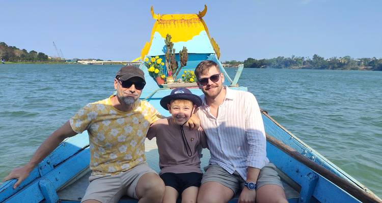 Familia sonriendo en un barco en un río bajo el sol.