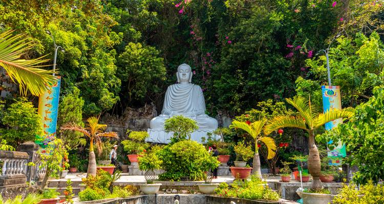 Une grande statue de Bouddha dans un cadre de jardin tranquille.