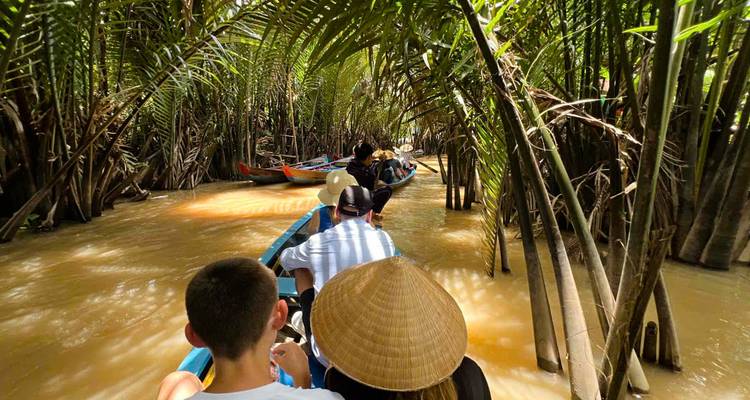 Personas remando por un estrecho canal bordeado de árboles.