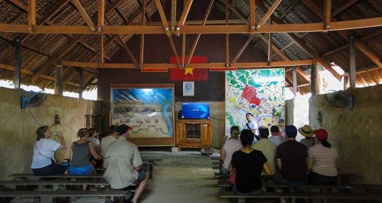 Grupo de turistas sentados en el interior de un refugio con mapas en las paredes.