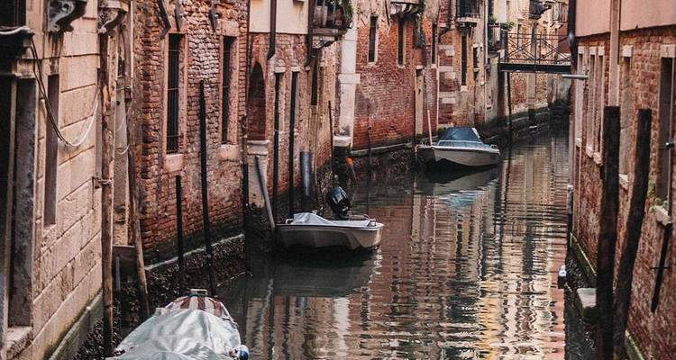 Historic Venetian canal with small motorboats floating on the water.