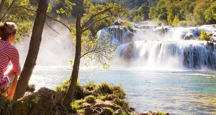 Persona sentada junto a una hermosa cascada.