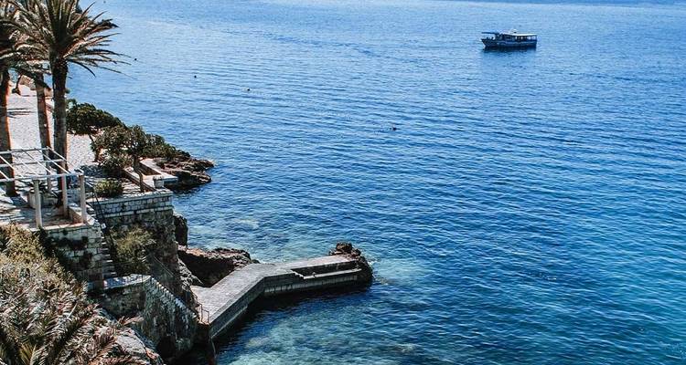 Una serena zona costera con un sendero que conduce al mar bajo cielos azules.