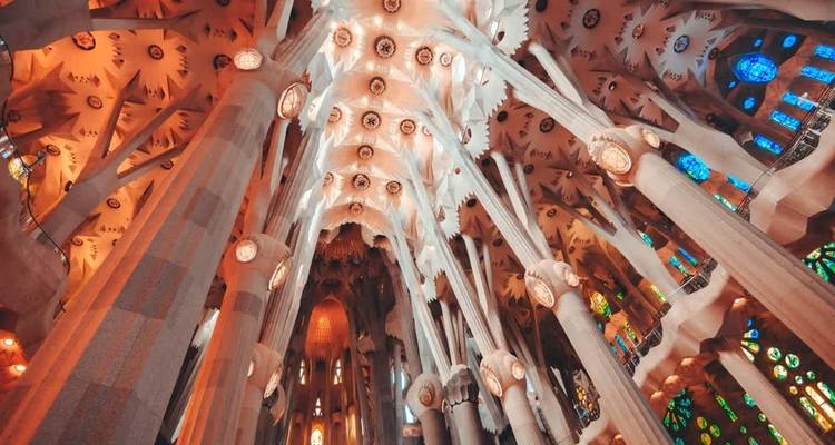 Vista interior de una gran catedral con arquitectura intrincada y coloridas vidrieras, probablemente la Sagrada Familia.