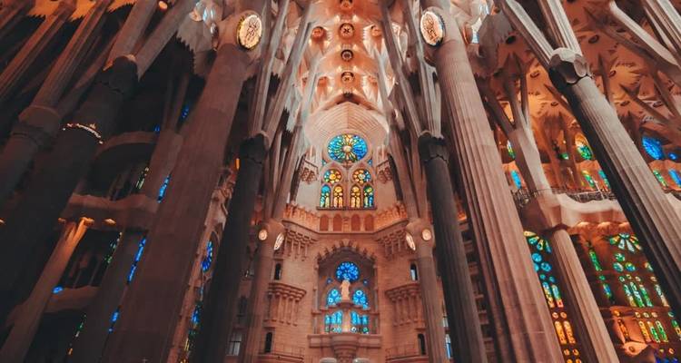 Interior de una gran catedral con vidrieras y columnas.