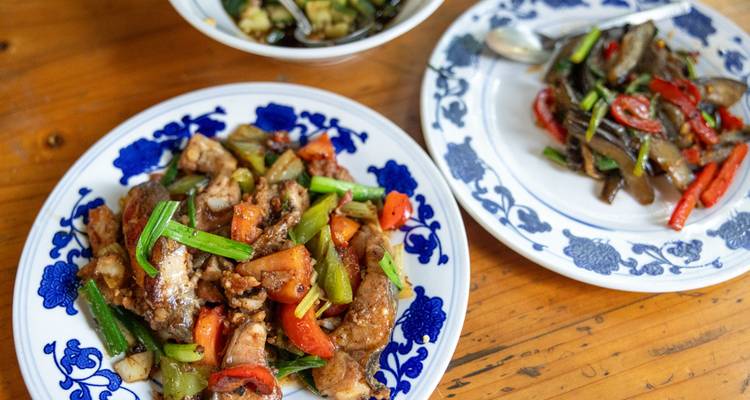 Vue rapprochée de plats chinois savoureux aux légumes et à la viande, présentés sur une table en bois.