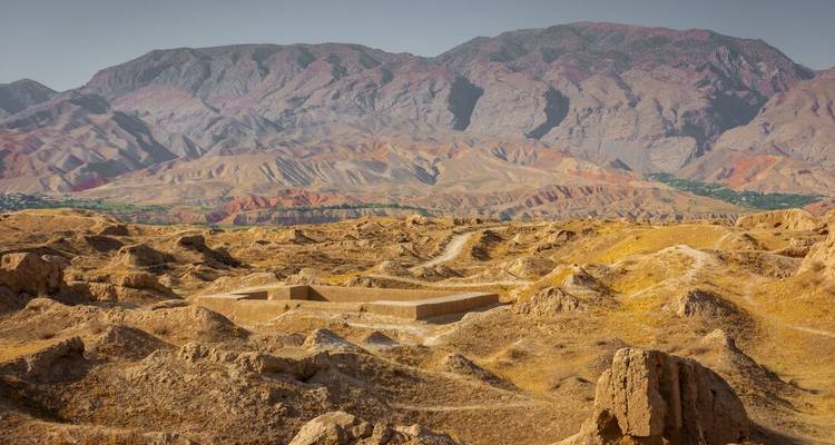 Vue panoramique d'un paysage sec et vallonné avec des vestiges de structures.