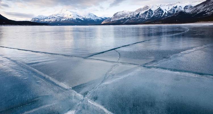 Lago congelado con montañas nevadas circundantes.