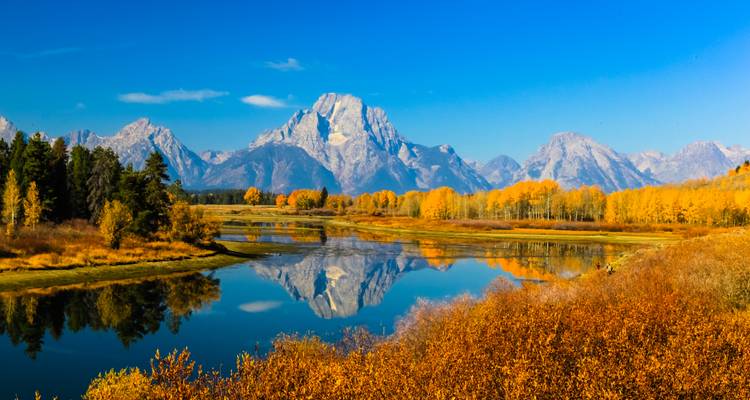 Spiegelartige Reflexion der Tetons und goldenen Herbstbäume in einer ruhigen Biegung des Snake River.