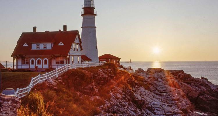 Leuchtturm auf einer felsigen Klippe bei Sonnenuntergang mit Ozean im Hintergrund.