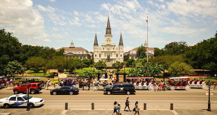 St. Louis Cathedral in New Orleans with people and horse-drawn carriages.