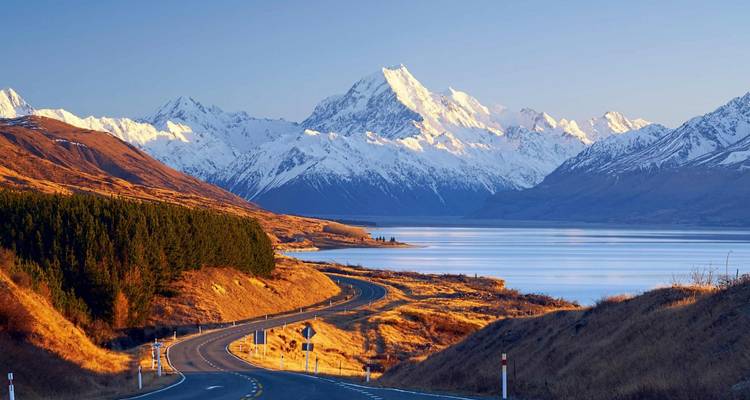 Une route menant à une montagne enneigée près d'un lac.