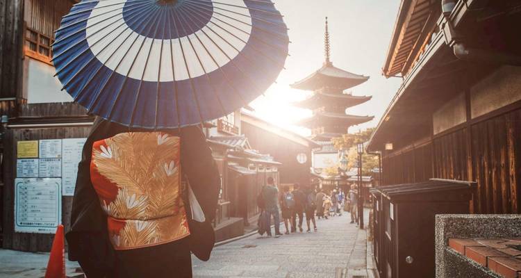 A person in traditional attire with a pagoda in the background.