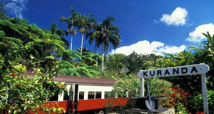 Kuranda train station sign with surrounding lush greenery.