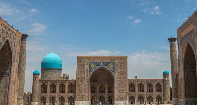Grand Registan Square met prachtig versierde madrasas en levendige blauwe koepels onder een heldere hemel.