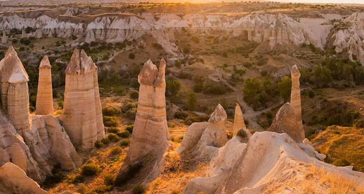 Les formations rocheuses surréalistes de cheminées de fées de Cappadoce brillent sous un ciel de coucher de soleil chaleureux.