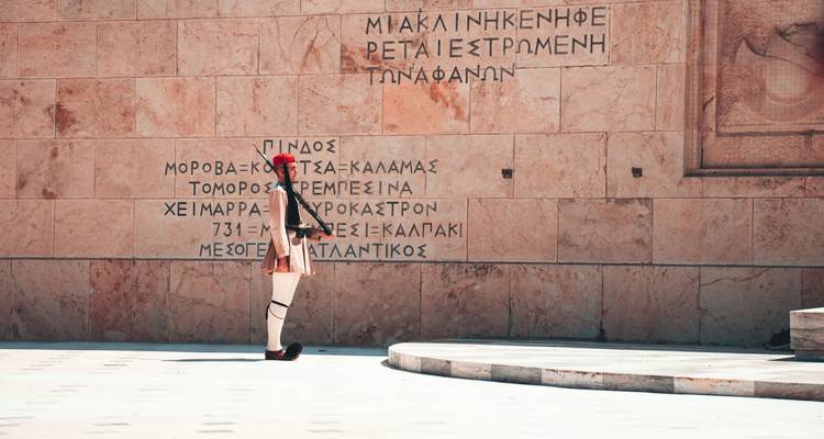 Garde Evzone en uniforme traditionnel se tenant devant des inscriptions grecques au Tombeau du Soldat inconnu à Athènes