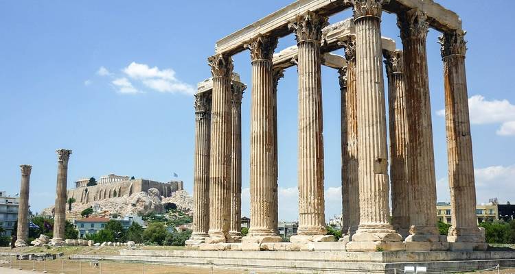 Les anciennes colonnes corinthiennes du Temple de Zeus Olympien avec l'Acropole s'élevant à l'arrière-plan sous un ciel bleu clair