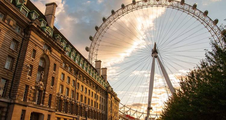 Das London Eye Riesenrad erhebt sich bei der goldenen Stunde über County Hall, während Sonnenstrahlen durch die Speichen filtert.
