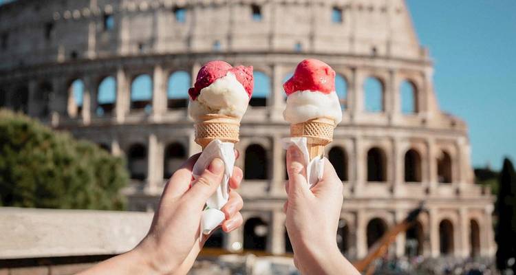 Dos conos de helado sostenidos en alto con el icónico Coliseo difuminado en el fondo.