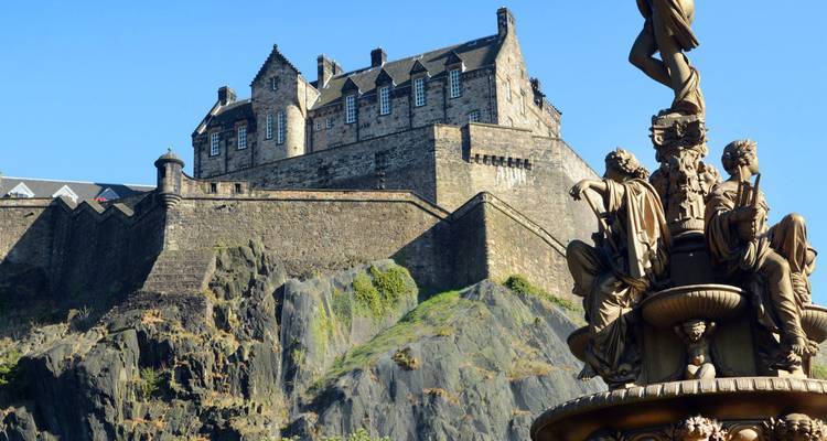 Le château d'Édimbourg s'élève sur son rocher escarpé à côté de la fontaine ornée de Ross sous un ciel bleu.