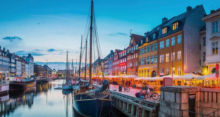 Une scène pittoresque de canal au crépuscule avec des bâtiments éclairés et des bateaux.