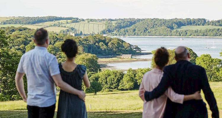 Deux couples se tiennent bras dessus, bras dessous, admirant un estuaire irlandais tranquille et la campagne verdoyante vallonnée.
