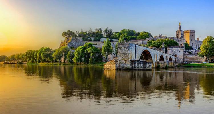 Historische Brücke und Palast am Fluss bei Sonnenuntergang.