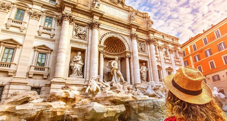 Mujer con sombrero de paja admira las esculturas ornamentadas de la Fontana di Trevi de Roma bañadas en luz cálida.