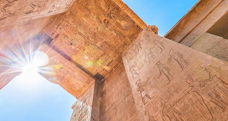 Vue en contre-plongée de colonnes de temple égyptien antique éclairées par le soleil et gravées d'hiéroglyphes