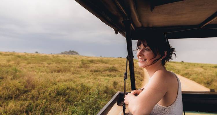 Woman enjoying a safari ride, looking out from a jeep.