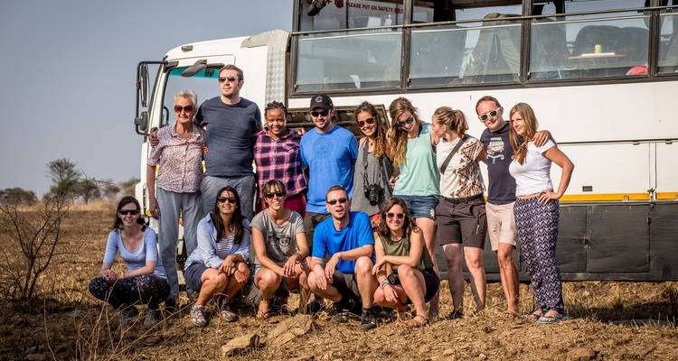 A group of people posing in front of a tour bus.