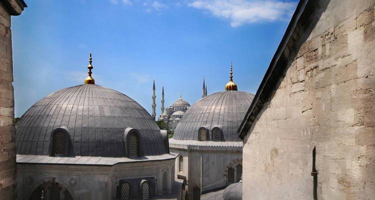 Domes and minarets of a mosque under a clear blue sky.