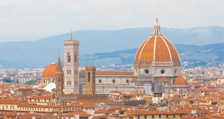 Icónica cúpula y campanario del Duomo de Florencia elevándose sobre los tejados de terracota de la ciudad histórica.