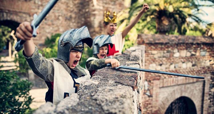 Niños vestidos con trajes medievales con espadas alzadas desafiantemente.