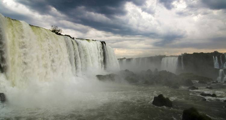 Un poderoso telón de las Cataratas del Iguazú retumbando en la niebla bajo un cielo amenazante.