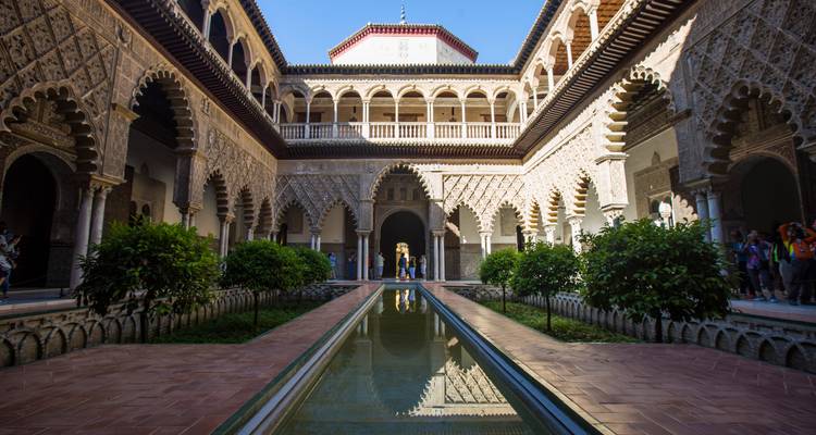 Patio soleado con estanque reflectante dentro del Real Alcázar de Sevilla