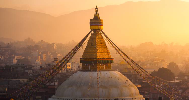 Stupa at sunset with a cityscape in the background.