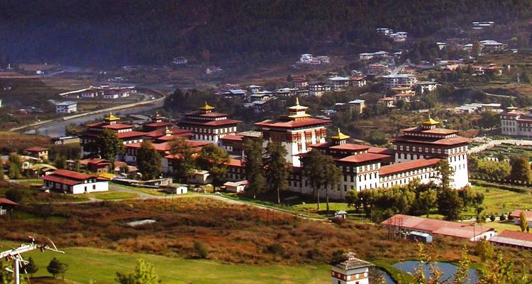 Aerial view of a large Dzong with mountains in the background.