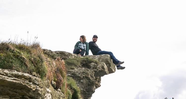 Twee mensen die op een rotsachtige klif zitten met een eenvoudige achtergrond.