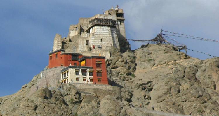 Een historisch klooster gelegen op een rotsachtige heuvel onder een bewolkte hemel.