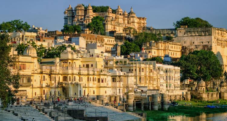 Historic city buildings overlooking a lake at sunset.